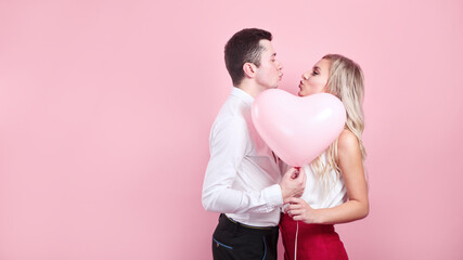 Fototapeta na wymiar Valentines day. Beautiful romantic couple with heart balloon on pink background