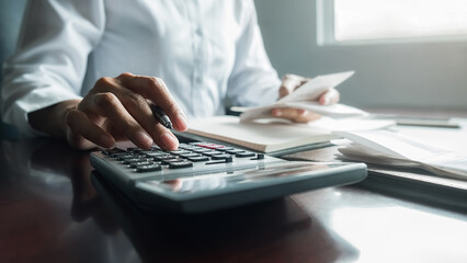 Woman with bills and calculator. Woman using calculator to calculate bills at the table in office. Calculation of costs.