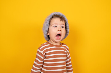 Boy scream mouth open, boy opens his mouth and yells loudly. Child in warm knitted hat emotionally tells. Emotional Toddler, protest. Crisis of three years, surprised baby boy