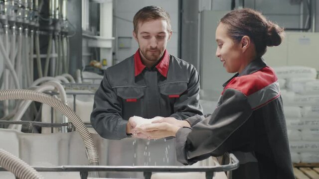 Slow-motion waist-up footage of multi-ethnic factory workers discussing polypropylene production holding transparent granules in hands