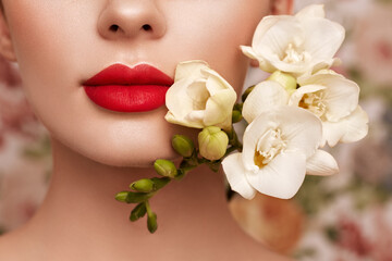 Beautiful model with a flower. Perfect woman face makeup close up. Red lipstick