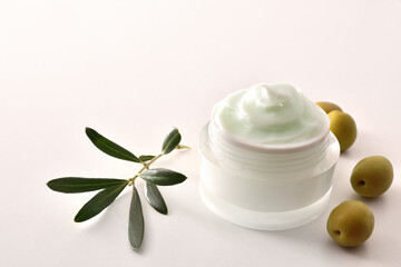 Olive moisturizing cream for skin on white table elevated