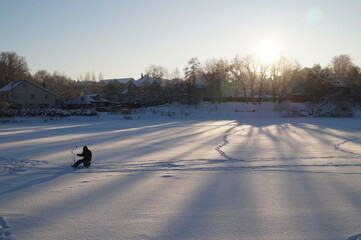 Naklejka premium a fisherman on a frozen lake