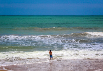 Fototapeta na wymiar Um garoto tomando banho na praia