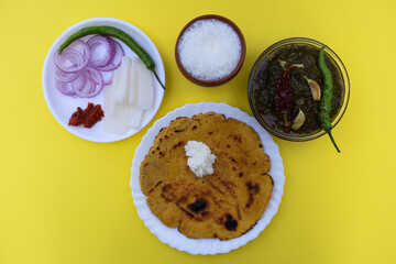 India Makki roti and sarson saag with onion chilly salad and earthened glass of sweet lassi in an authentic way with white butter and green chilly. Punjabi traditional style food