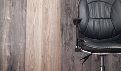 Black leather office chair in wooden background.