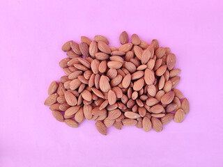 Top view of unpeeled heap of almonds isolated on pink background.