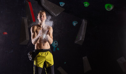 Young man applying magnesium powder before climbing in bouldering gym
