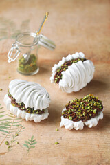 French Vanilla Meringue Sandwich Cookies with Chocolate Ganache filling and Pistachios.