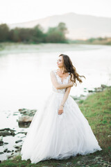 Fototapeta na wymiar Portrait of stunning bride with long hair standing by the river