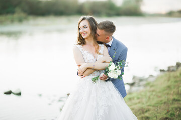 Wedding couple, groom and bride hugging, outdoor near river