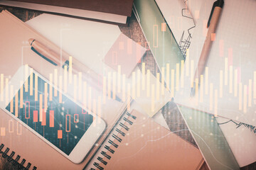 Multi exposure of forex graph hologram over desktop with phone. Top view. Mobile trade platform concept.