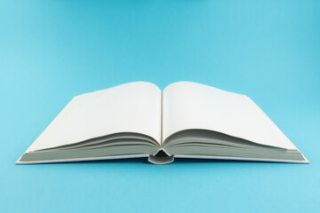 open hardcover book with blank white pages on blue background