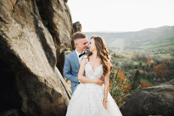 Happy wedding couple posing over beautiful landscape in the mountains