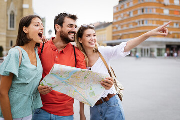 Happy traveling tourists sightseeing with map and having fun - obrazy, fototapety, plakaty
