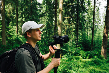 Two friends create a video blog on camera with a stabilizer in a mountain hike. Video maker shoots in the mountains a man in a white T-shirt.