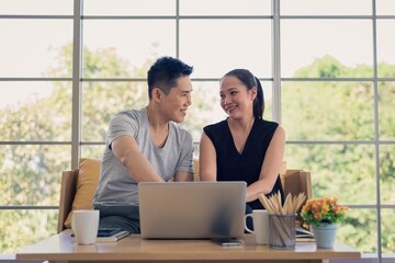 Asian man and woman family in casual outfit sitting in living room using laptop together in happy and smile emotion