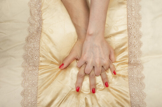 LGBT concept. Women holding hands on the bed. Hands of couple of homosexual women on yellow set sail champagne color pillow. Same sex love. Lesbi relationships.