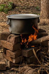 An aluminum utensil on a temporarily made fire oven by bricks.