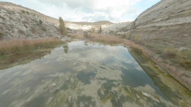 Stone mining industrial quarry in mountain terrain from sport drone above. Lakes formed in quarry areas after rocks mining. Aerial speed shooting from fpv sport drone.