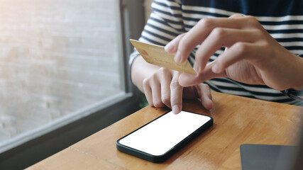 Close up of man is hands holding cell telephone and credit card with blank copy space scree for your advertising text message or promotional content, shoping online.