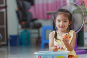 Asian kid plays in the toy kitchen, cooks a hamburger