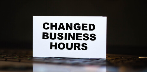 CHANGED BUSINESS HOURS on white business card with computer background