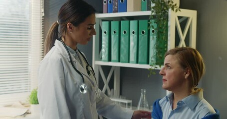 Close-up of kind caring female therapist saying comforting words to upset middle-aged woman during appointment. Doctor supporting cancer positive patient.