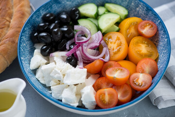 Closeup of greek salad with sliced red and yellow tomatoes, cucumber, feta cheese, black olives and red onion, selective focus