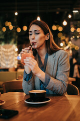 Beautiful young adult woman sitting in a nice restaurant or coffee bar and enjoying in fresh good coffee drink.