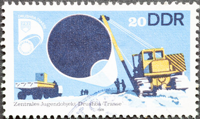 GERMANY, DDR - CIRCA 1978  : a postage stamp from Germany, GDR showing laying a piece of pipe a...
