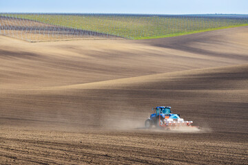 Tractor with seed drill in early spring landscape