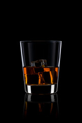 Glass with whiskey and ice on black background