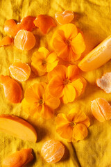 Obraz na płótnie Canvas orange primroses and fruits on the orange linen fabric