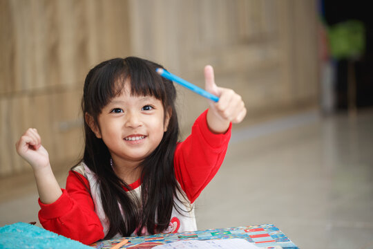 Asian little girl learning and writing in notebook with pencil