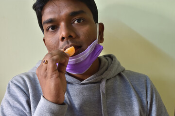 Man is sick with flu and wears a medical mask eating fruits enriched with vitamins c. Selective...