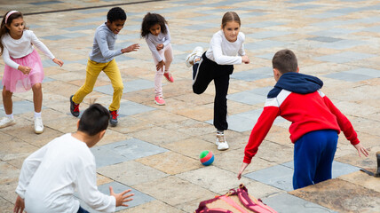 Group of happy schoolchildren playing football together on the street © JackF