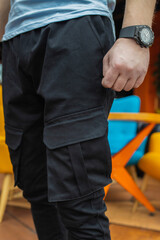 Image of a detail of a man's resting at the side of his pant leg with his thumb in his pocket