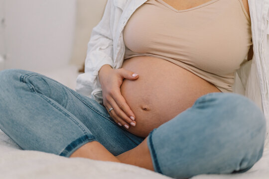 Attractive pregnant woman is sitting in bed and holding her belly. Pregnancy Concept.