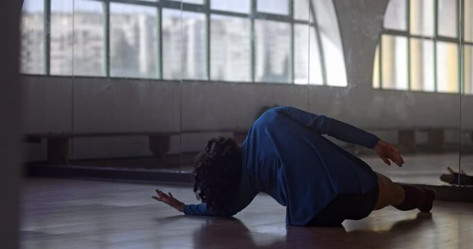 African-american woman dancing lying on floor in dance studio
