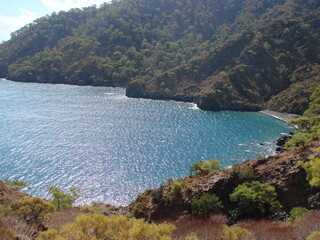 View from the hiking trail to the azure surface of the sea bay that reflects the sun's rays on the...