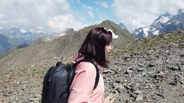 Close up of young woman walking in highlands. Side view of female tourist with backpack going in mountainous terrain on sunny day.