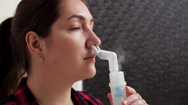 Close-up of a woman inhaling nasal passages of steam using a nebulizer, copy space