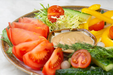 vegetable plate of fresh tomatoes, peppers, cherry tomatoes and cucumbers with sauce. vegetarian dish