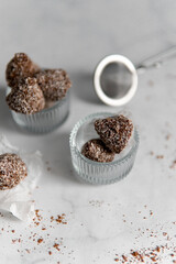 Homemade chocolates with coconut flakes and cocoa powder on a white marble table. Sweets background. view from above.
