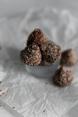 Homemade chocolates with coconut flakes and cocoa powder on a white marble table. Sweets background. view from above.