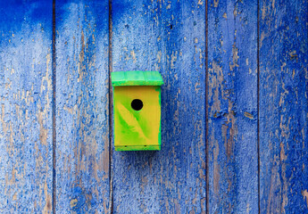 one hand-made birdhouse on a blue wooden wall in the spring garden