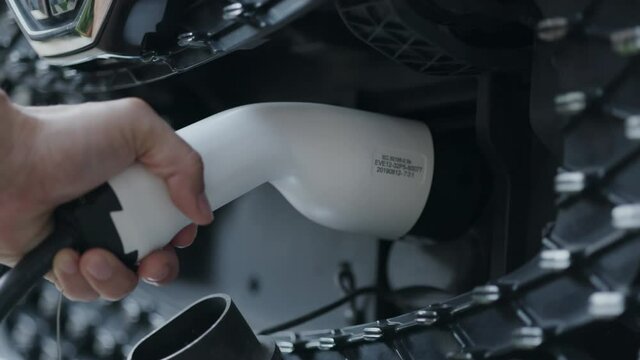 Close-up of charging hand to power the electric Car. Automotive technology of the future. Save energy And protect the environment. Charging pump at home