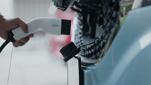 Close-up of charging hand to power the electric Car. Automotive technology of the future. Save energy And protect the environment. Charging pump at home