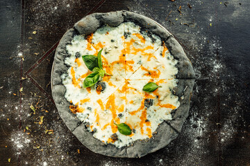 A top view of appetizing pizza with black dough and various vegetables